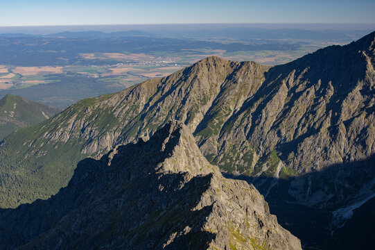 Aerial view of jagged peaks pierce the sky, revealing a tapestry of green valleys and distant settlements, Jahnaci stit peak, Presov Region, Slovakia.