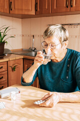 An elderly woman takes a large number of medications daily. Chronic disease treatment, aging, health problems, dementia and loneliness, home treatment, regular pill intake