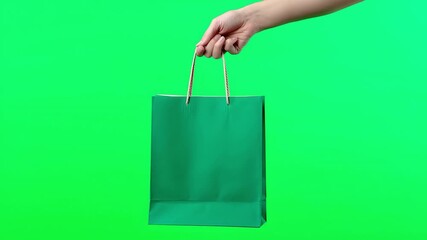 Gift of Purchase: A hand offers a vibrant green shopping bag against a vivid green backdrop, embodying the essence of gifting and retail.