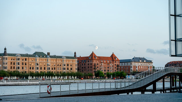 Moon over Copenhagen promenade canal at dusk with cityscape