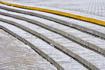 Concrete stone staircase covered with first snow at city pedestrian walkway. Slide fall injury danger, slippery steps. Frozen staircase covered with thin layer of winter snow