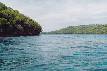 Naklejka premium Tropical seascape with two lush green islands divided by clear blue water under bright sky, symbolizing untouched beauty, balance, and harmony in remote natural environments