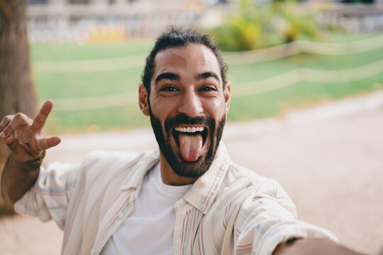 Man sticks out tongue while snapping selfie, expressing humor and playful attitude through digital self-portraits in spontaneous, bold and emotional tech interaction.