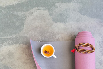 Flat lay featuring a rolled yoga mat and a cup of herbal tea with star anise. This image captures the holistic wellness and mindfulness of a yoga or Ayurveda practice.