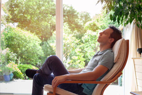 man relaxing at home after work, rest and relaxation for mental health and wellbeing, person with closed eyes sitting in armchair