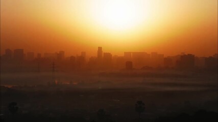 A beautiful time lapse of the sun rising behind an urban landscape of skyscrapers, turning the skies in different hues of orange, with clouds passing over a congested slum locality, Mumbai city, India