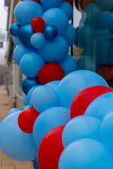 Bright blue and red balloons create a festive entrance on a busy city street during a cheerful celebration