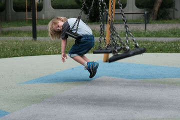 Dziecko bawiące się na huśtawce na placu zabaw © Przemysaw