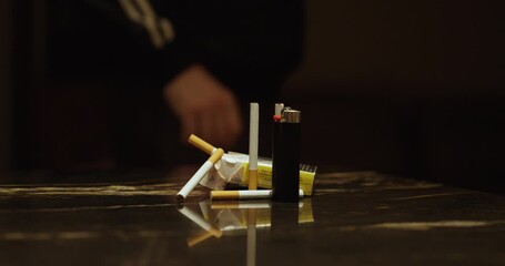 A man hesitates to grab cigarettes lying on a table, symbolizing nicotine addiction, temptation, and the challenge of quitting smoking and vaping.