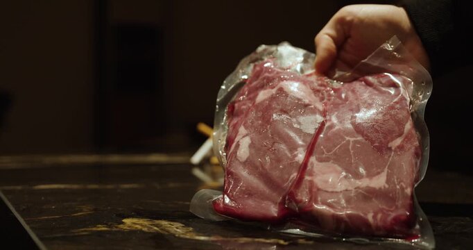 A hand holds a piece of vacuum-sealed meat, representing food preservation, extended shelf life, and hygiene in modern food storage.