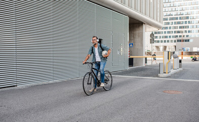 City commuter with headphones on head before, riding bike.