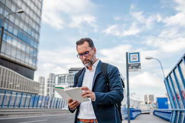 Mature man reading while waiting for bus.
