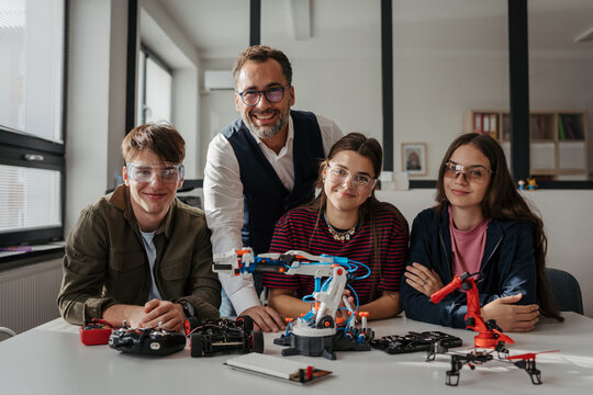 High school students working on robotics project with their teacher. - Powered by Adobe
