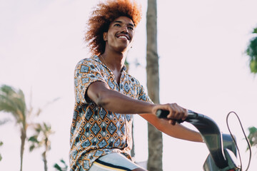 Upward view of young man riding shared red bicycle, smiling with freedom. Stock photo about eco-mobility, app-based commuting, and technology-enabled sustainable lifestyle concepts.