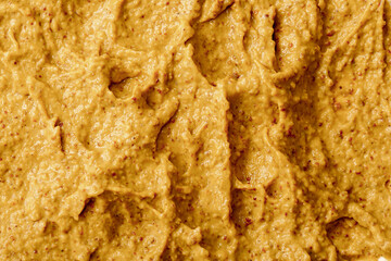 Mustard sauce with grains close-up. Hot spices as a background. Texture of Dijon mustard.
