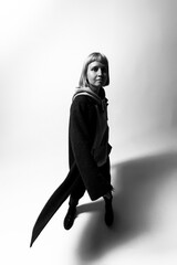 A model strikes a confident pose in a modern outfit, showcasing a blend of black and gray hues. The minimalist background highlights her presence at an indoor studio setting