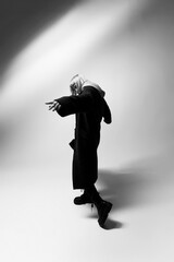 A person showcases their unique fashion sense while dramatically posing on a smooth, light background. The scene captures the energy and creativity of a modern photoshoot