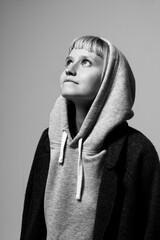 Soft natural light illuminates a young person gazing upward with a hopeful expression. Dressed in a snug hoodie and a coat, they embody a moment of introspection and aspiration
