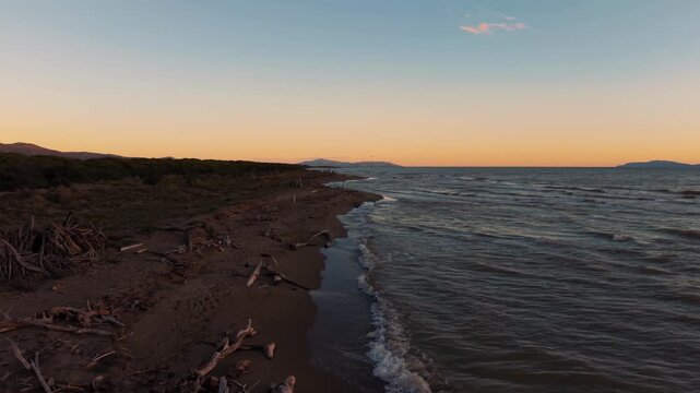 Seaside tipi made of driftwood illuminated by the colorful Tuscany sunset sky. Scenic Maremma aerial