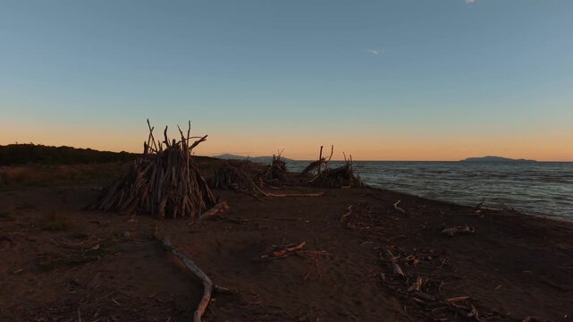 Peaceful evening twilight over Parco Maremma with driftwood tipi and pine forest along the sea beach