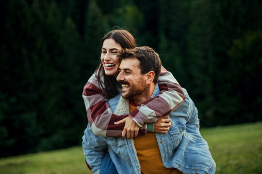 Happy couple enjoying piggyback ride in nature
