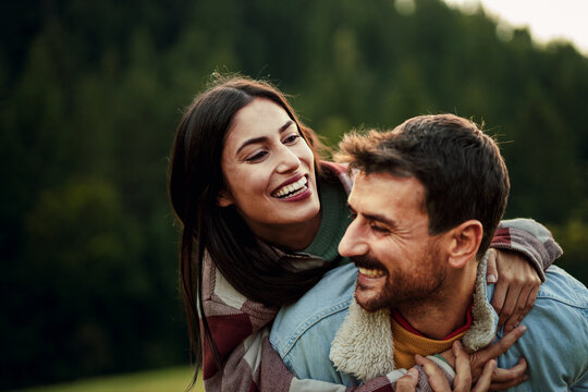 Happy couple enjoying piggyback ride in nature