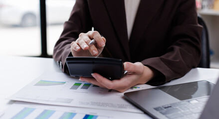 Professional calculator to check analyzing financial data graphs, charts on laptop display at a modern workspace. Financial analysis or business evaluation concept
