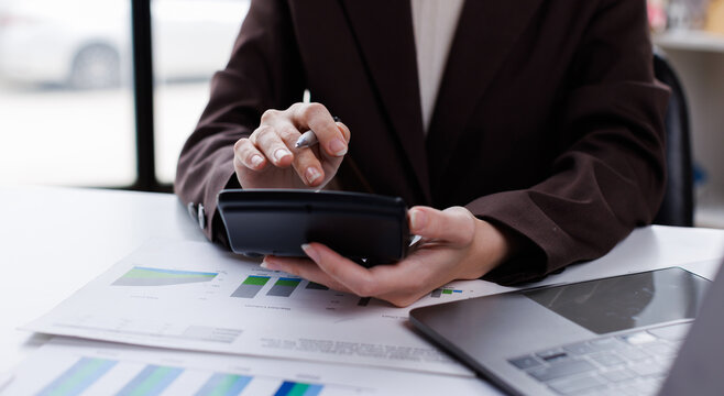 Professional calculator to check analyzing financial data graphs, charts on laptop display at a modern workspace. Financial analysis or business evaluation concept
