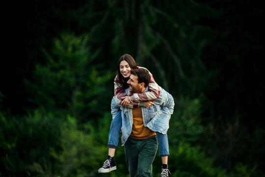 Happy couple enjoying piggyback ride in nature with love