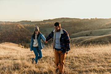 Couple holding hands walking uphill during autumn sunset
