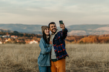 Happy couple taking selfie enjoying autumn nature