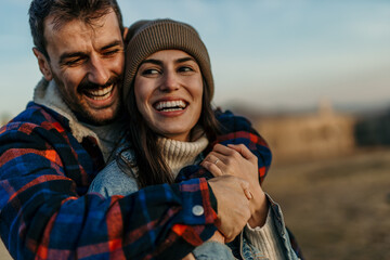 Happy couple hugging outdoors enjoying autumn day