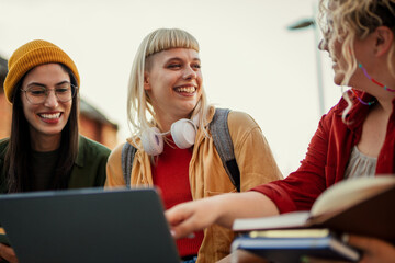 Diverse students collaborating learning outdoors using laptop