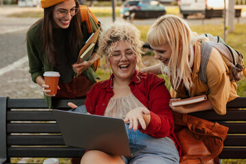Diverse students laughing while watching content on laptop