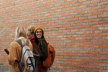 College students walking by brick wall smiling