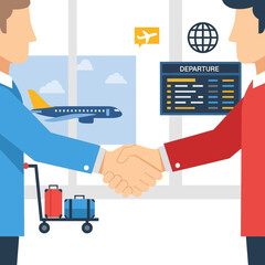 Two men shake hands near a luggage cart and airport departure information.