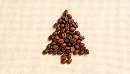 Coffee beans arranged into a Christmas tree shape on beige linen background. Creative festive flat lay.