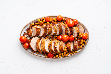 Roast pork tenderloin served with chickpeas and tomatoes in plate