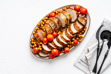 Roast pork tenderloin served with chickpeas and tomatoes in plate