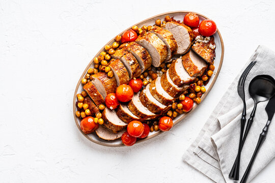 Roast pork tenderloin served with chickpeas and tomatoes in plate