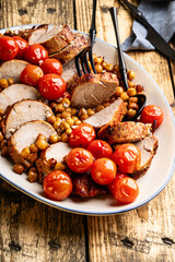 Roast pork tenderloin served with chickpeas and tomatoes in plate