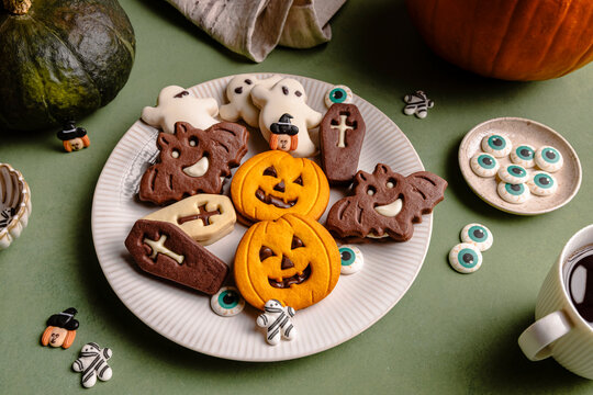 Halloween cookies on decorative plate over green table