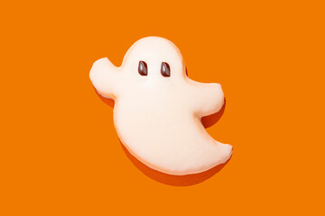 Ghost-shaped Halloween cookie on an orange background
