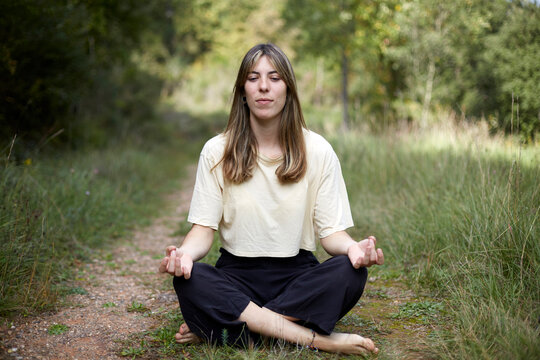 Woman meditating peacefully in a serene forest setting