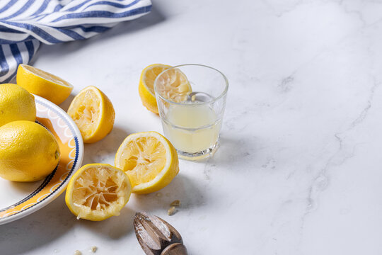 Fresh lemons with juice and wooden squeezer on marble
