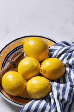 Fresh lemons on decorative plate with wooden reamer
