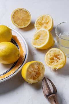 Fresh lemons, juice, and wooden reamer on marble surface