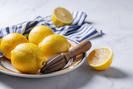 Fresh lemons on a marble surface with citrus reamer