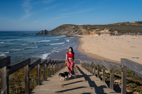 Woman walking dog along Praia da Amoreira boardwalk