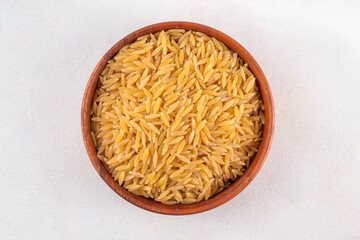 Raw uncooked orzo pasta, Italian dry pasta risoni orzo in bowl on table, copy space